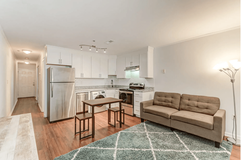 a living room with a couch and a kitchen with a refrigerator